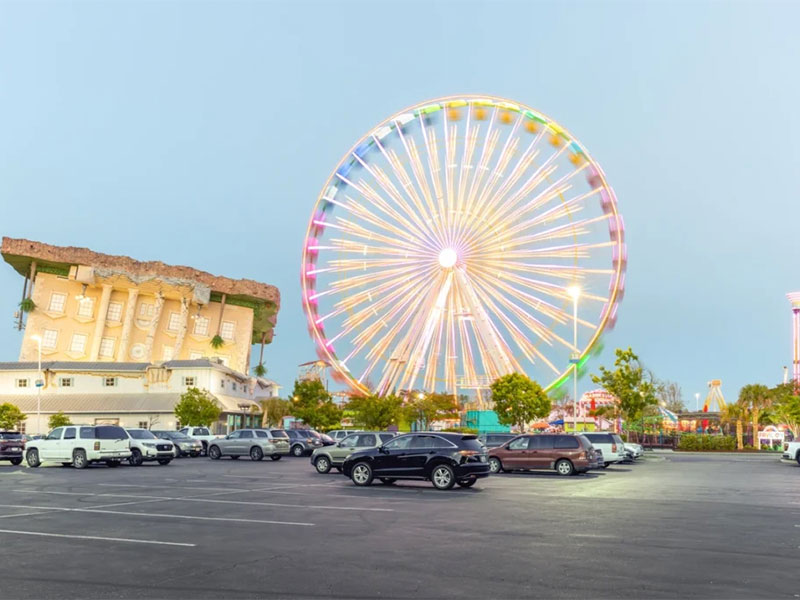 Large Ferris wheel near a parking area.