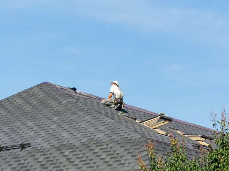 Contractor installing shingles on a residential roof.