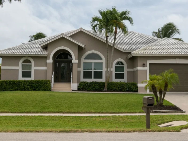 Single-story house with a tiled roof and palm trees.