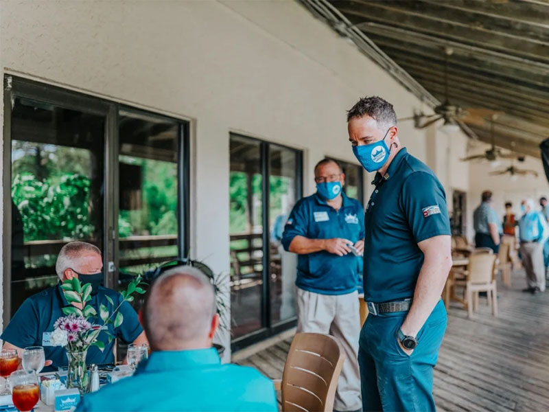 Roofing contractors meeting outdoors at a venue.