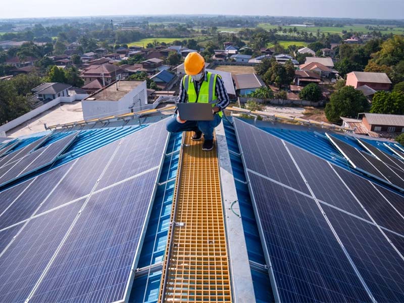 Technician inspecting installed rooftop solar panels.