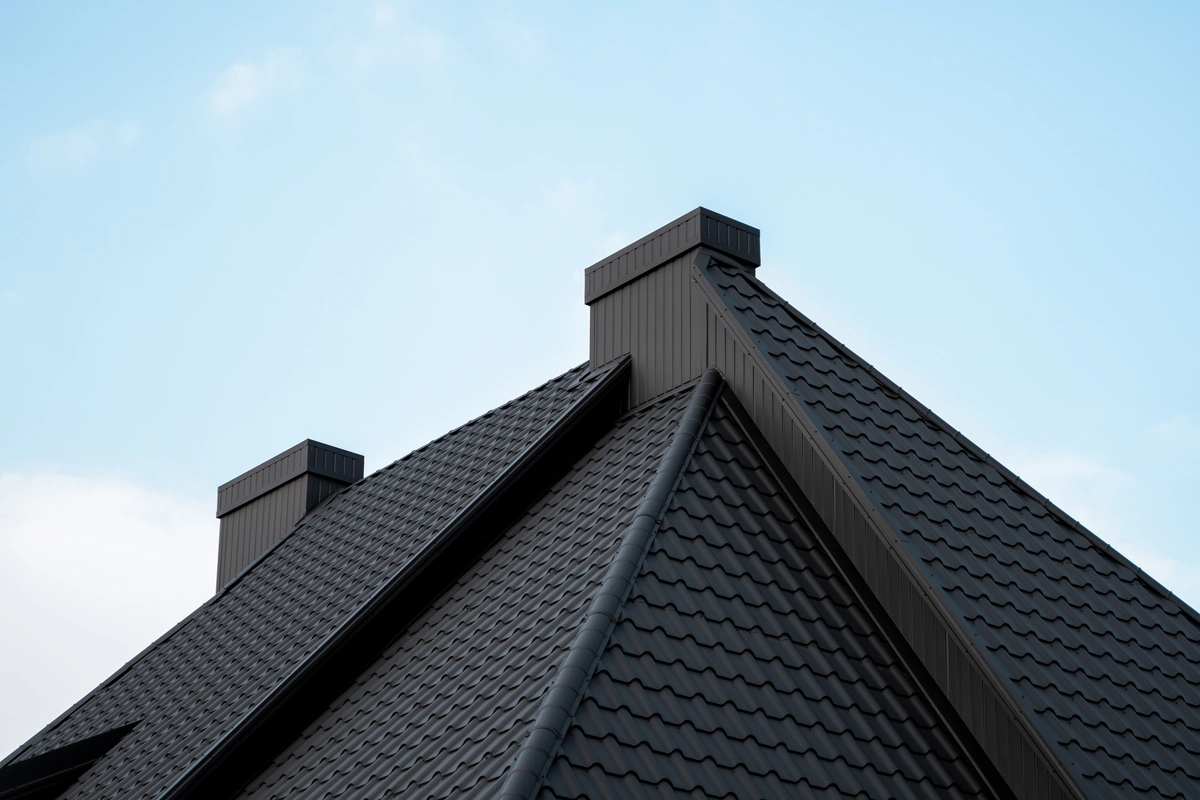 house roof with black metal tiles against blue sky