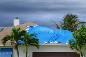 blue tarp on a damaged roof with dark skies in the background