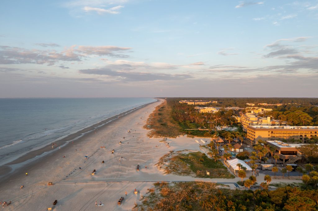 Bird's-eye view of Coligny beach on Hilton Head Island. Ocean view at sunset with trees and hotels in the foreground