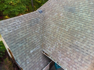 damaged gray roof with white chalk circles around damaged areas