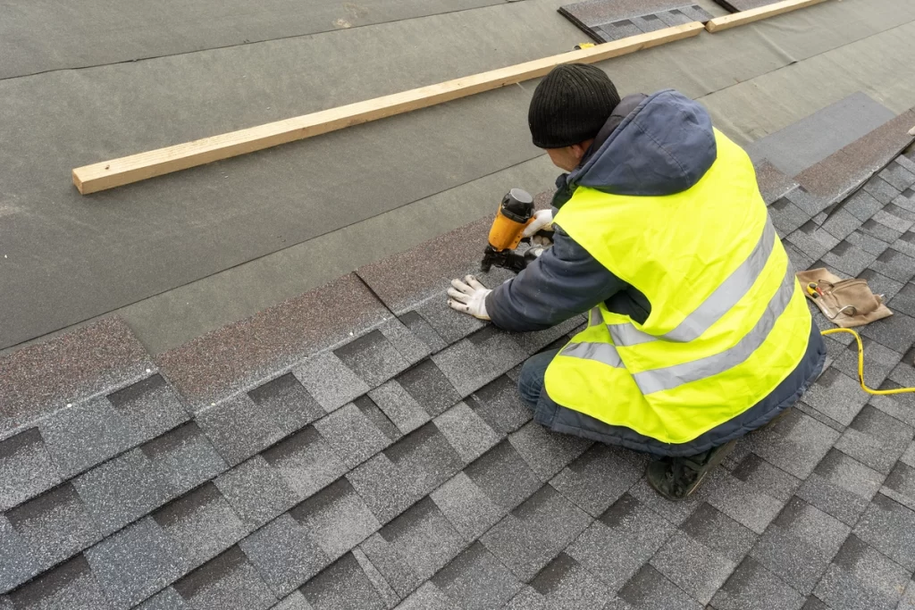 a roofer installs asphalt dimensional shingles