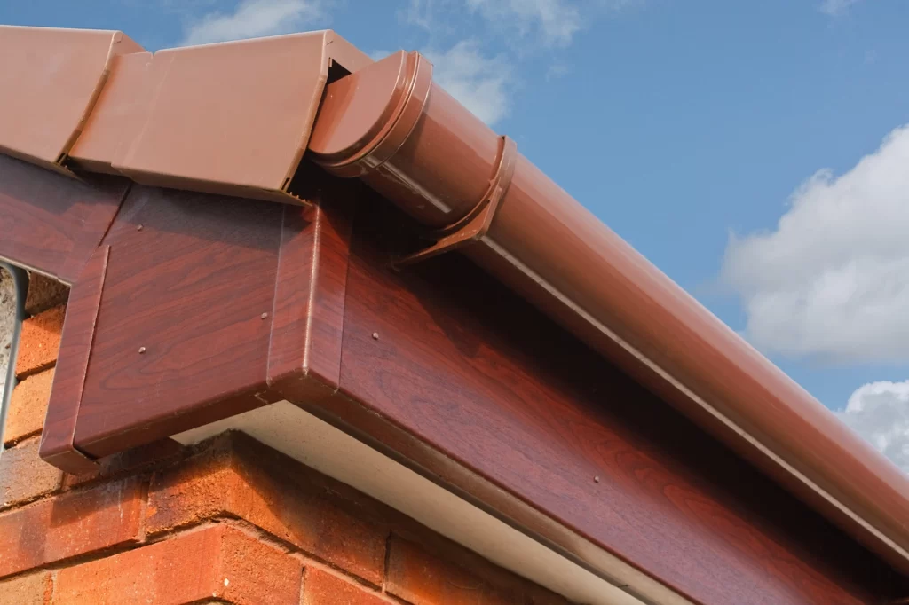 close up of roof fascia on house in maroon color with metal seamless gutters