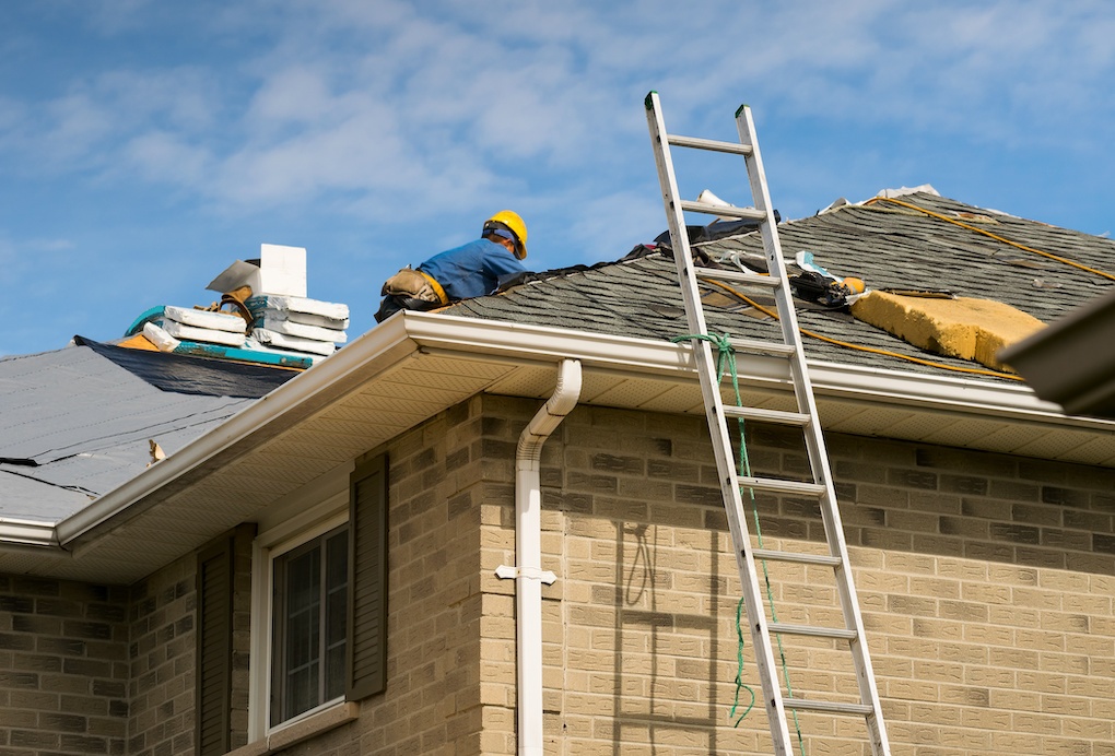 Roof worker installing new shingles on a roof; roof repair cost