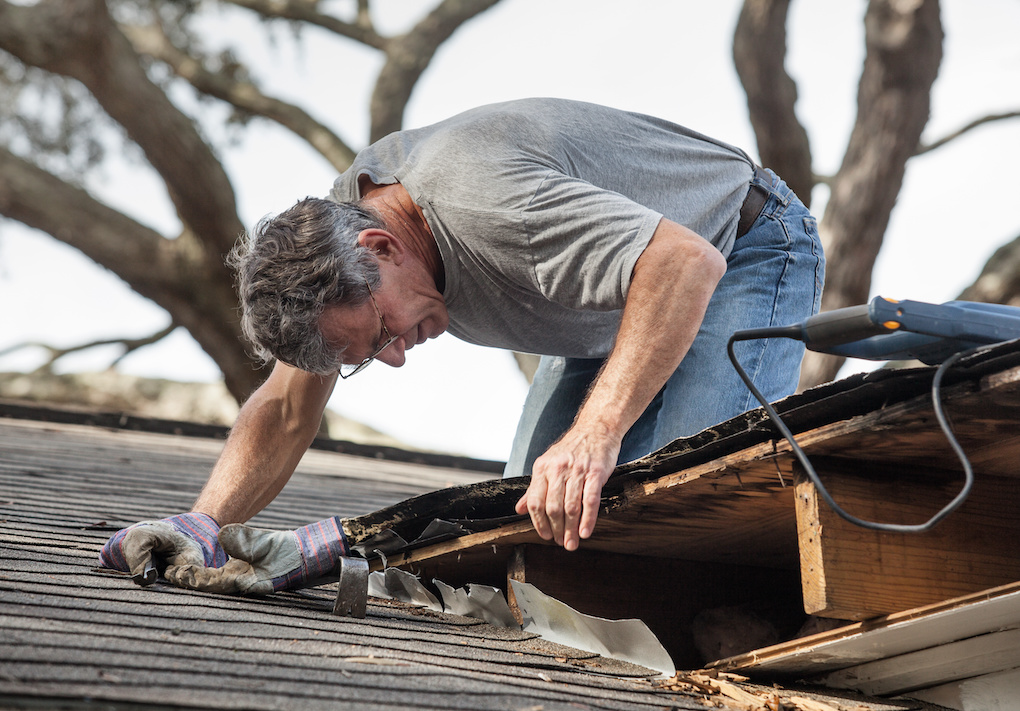 man examining sagging roof deck while discussing roof repair cost