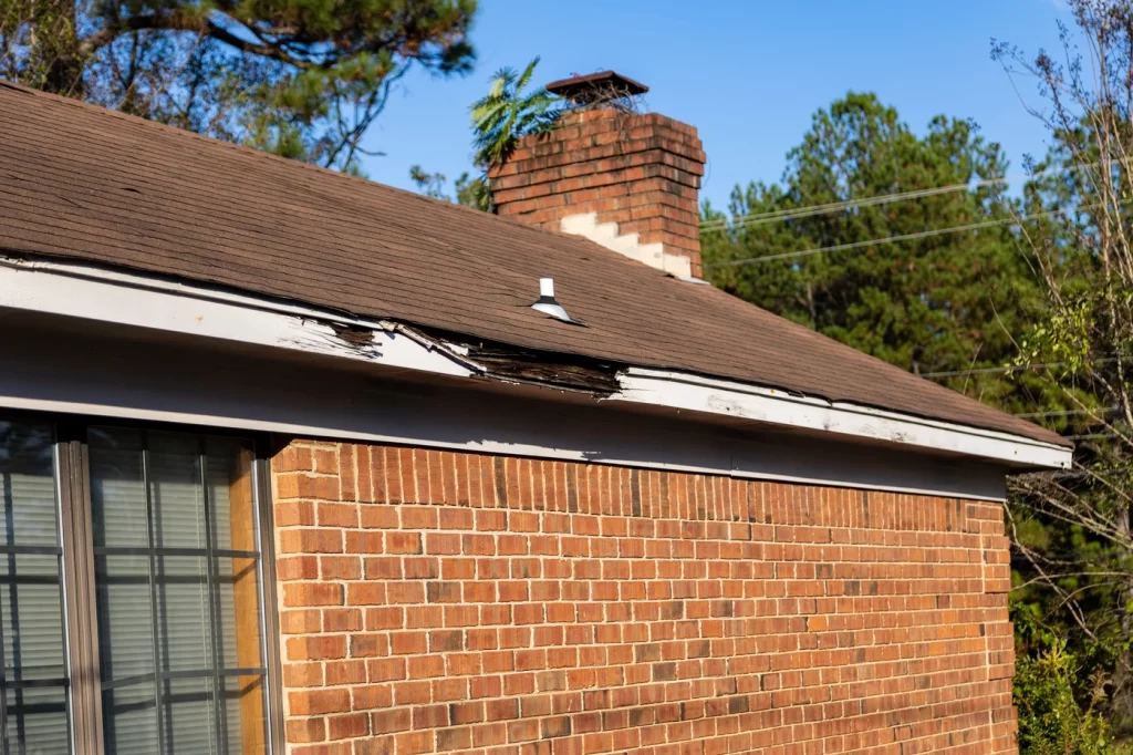 brick home with rotting roof fascia and older roof shingles