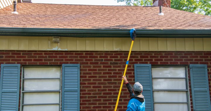 what causes mold on roof shingles-man standing on ground cleaning roof materials