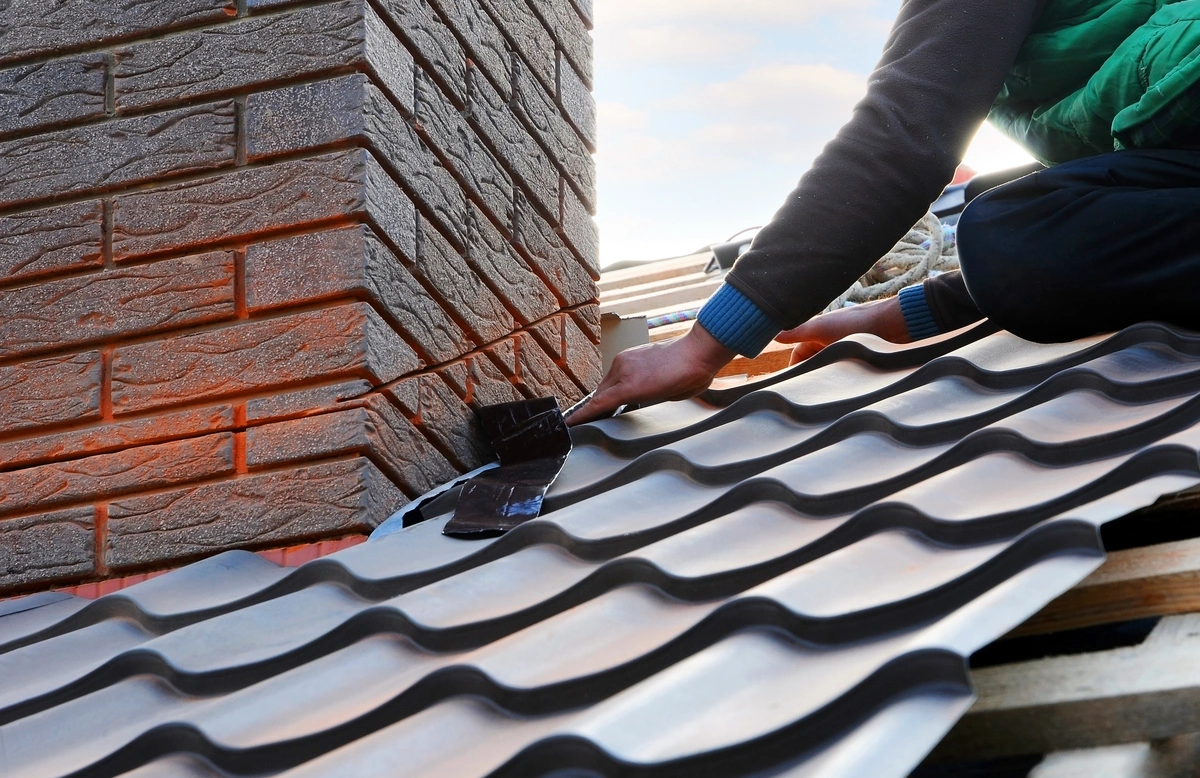 worker installing metal tiles around the chimney