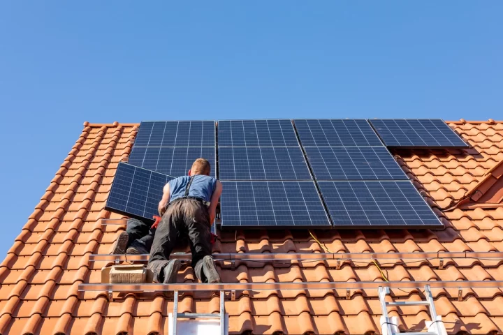 workers installing solar panels on tile roof