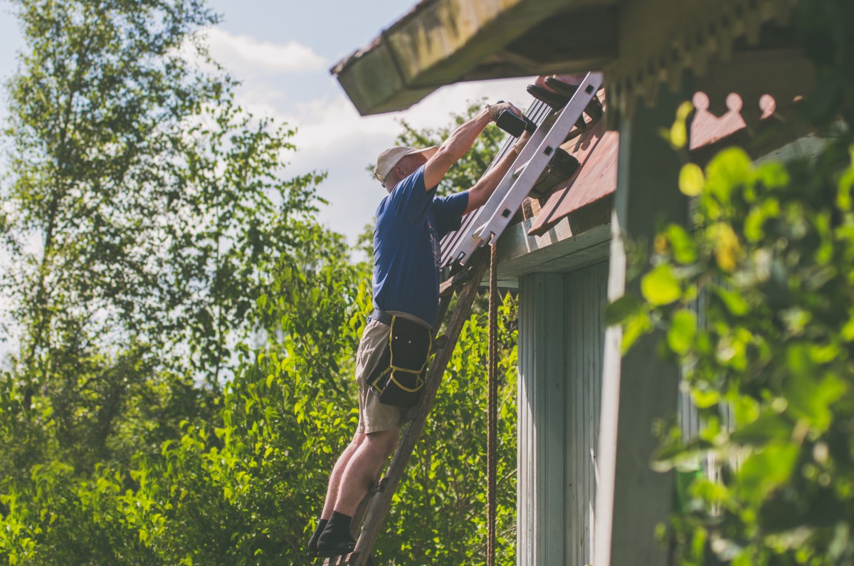 DIY roof repair being performed on a ladder