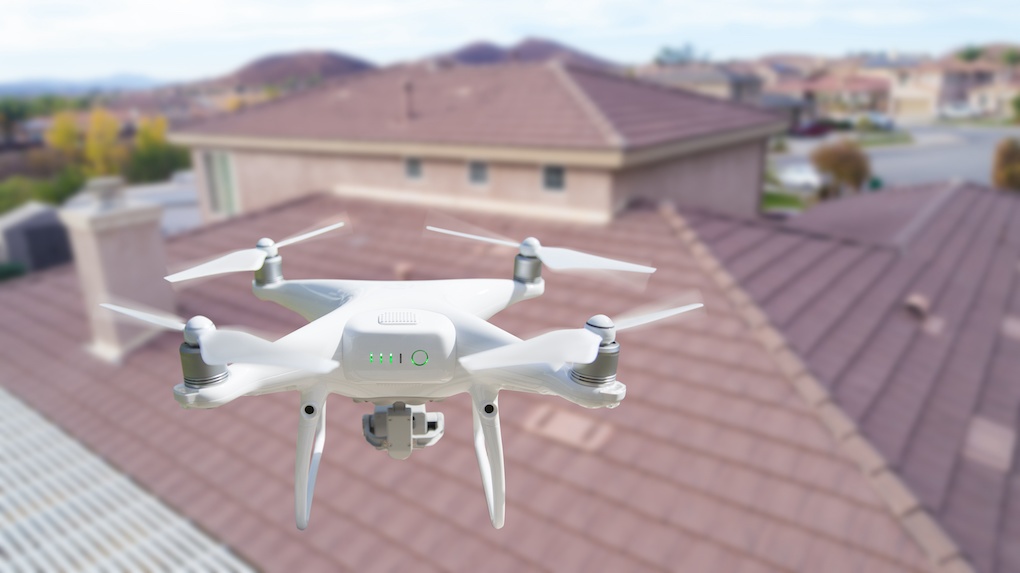 Unmanned Aircraft System (UAV) Quadcopter Drone In The Air Over House doing drone roof inspection