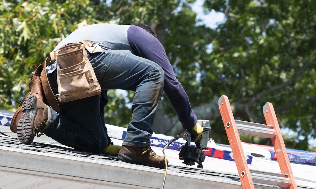 A contractor is kneeling on a residential roof; how long does it take to replace a roof