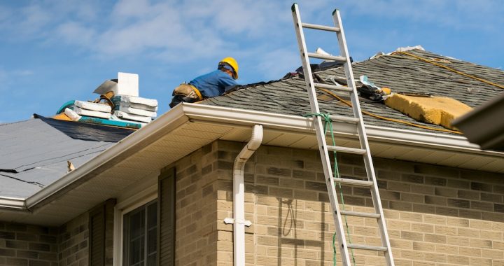 Roof worker installing new shingles on a roof; roof repair cost